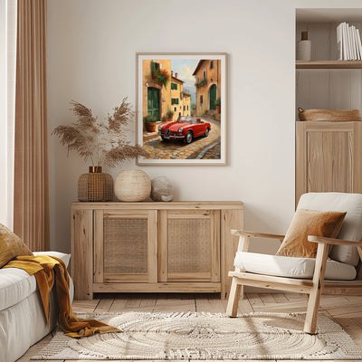 Vintage car home decor print featuring a red classic car on a cobblestone street in a framed wall art above wooden sideboard